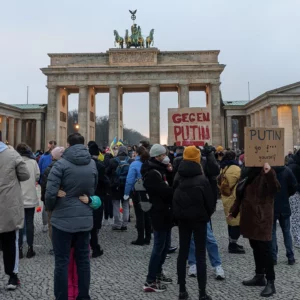 peserta demo mengangkat poster protes di Gerbang Brandenburger